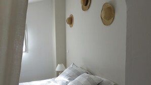 Ein Schlafzimmer mit einem Bett, Kissen, einem Nachttisch und drei Hüten an der Wand.