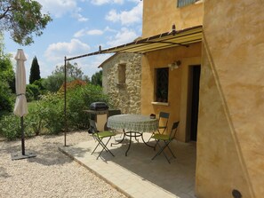 Une terrasse extérieure avec une table et des chaises, un barbecue et une pergola.