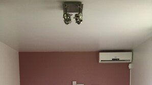 Une chambre à coucher avec un lit, deux lampes de chevet, un climatiseur fixé au mur et un tapis noir.