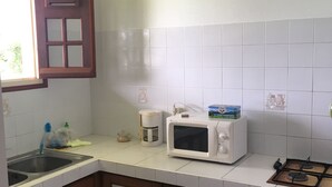 Une cuisine avec des carreaux blancs, un four à micro-ondes, une machine à café et des armoires en bois.