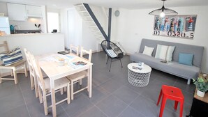 Un espacio habitable moderno con comedor, sofá, sillón rojo y una escalera.