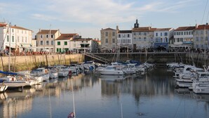 Marina con barcos amarrados, rodeada de edificios con comercios.