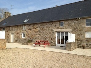 Traditional farmhouse with a small porch and stone walls.