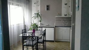 Una cocina compacta con una mesa de comedor, sillas, una planta en maceta y un reloj en la pared.