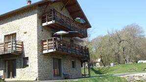 A stone building with a wooden balcony and a covered outdoor seating area. - Cottage in the heart of the Vercors national park, sleeps 11, fully equipped (Saint-Martin-En-Vercors)
