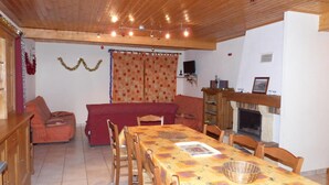 A cozy living room with a wooden ceiling, a fireplace, a dining table with chairs, and a sofa. - Cottage in the heart of the Vercors national park, sleeps 11, fully equipped (Saint-Martin-En-Vercors)
