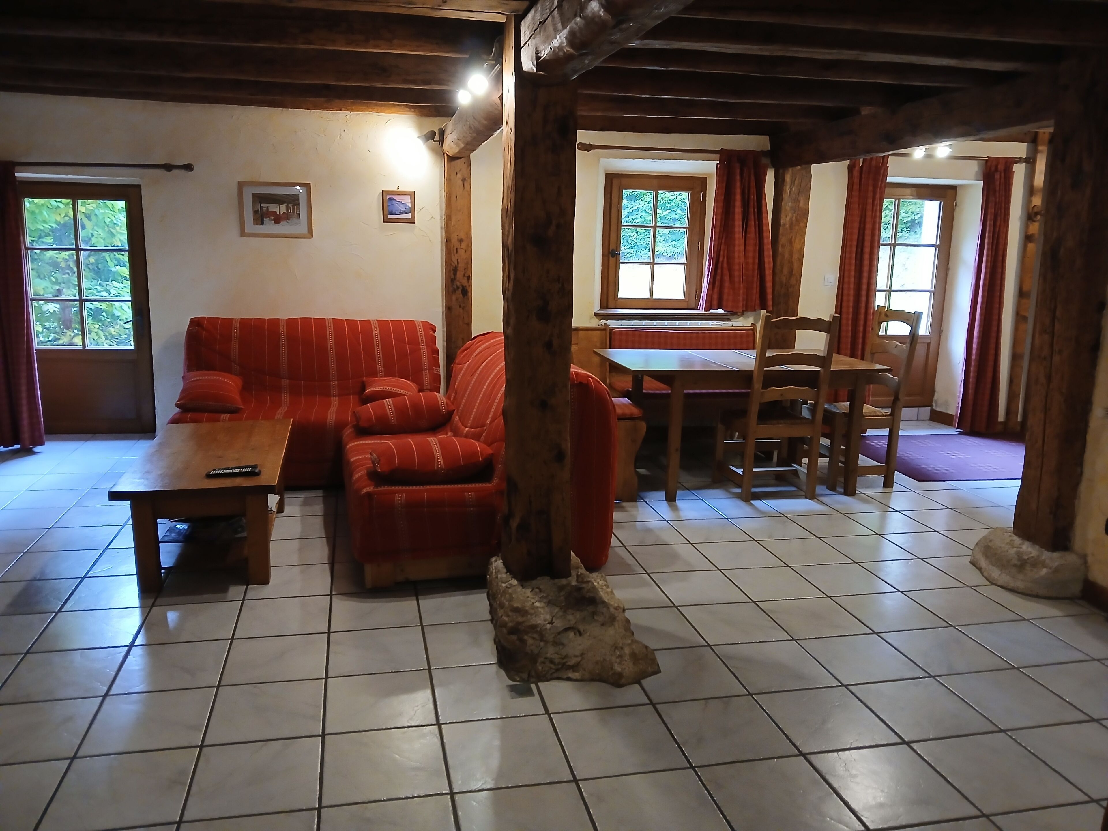 Een gezellige woonkamer met een bank, een houten tafel en een zithoek met stoelen.