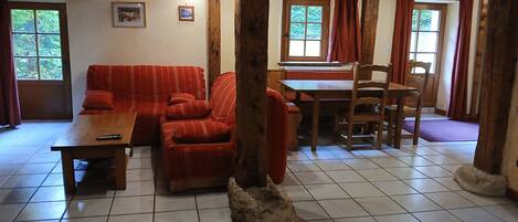 Een gezellige woonkamer met een bank, een houten tafel en een zithoek met stoelen.