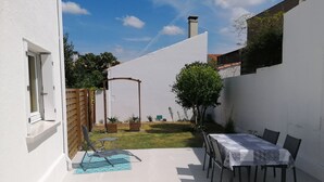 A patio with a table and chairs, a wooden fence, and a small garden area with potted plants. - Appt House 72M² 2/4 persons 50m SEA BEACH (Châtelaillon-Plage)