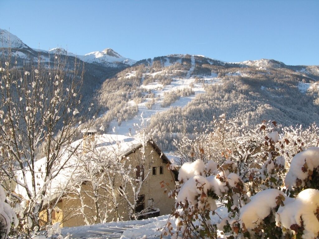 Un paysage montagneux enneigé, avec un bâtiment rustique au premier plan.