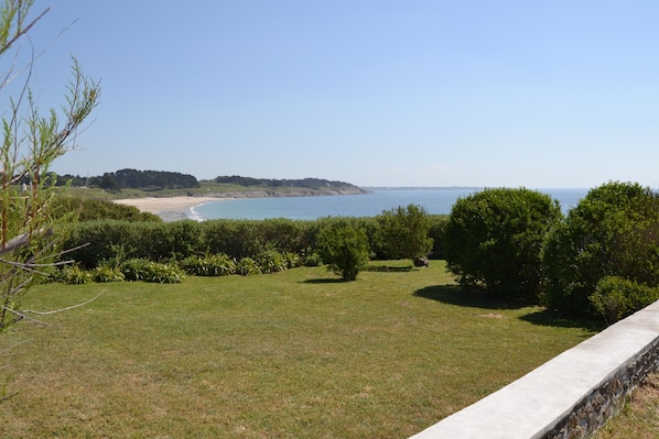 A grassy area with a view of the sea and distant hills.