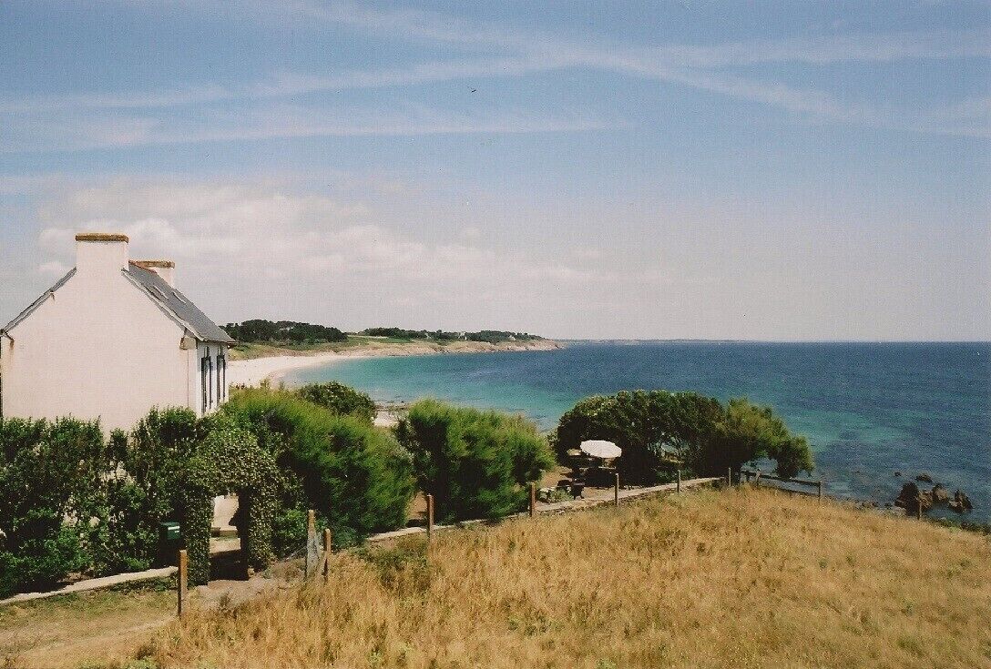 A coastal view with a white building, a sandy beach, and the sea.