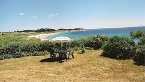 A table and chairs on a grassy area with a view of a beach and the sea. - Exceptional sea and island view. A haven for nature in a protected site (Névez)