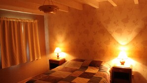 Een slaapkamer met een bed, twee nachtkastjes, een hanglamp en bloemenbehang.