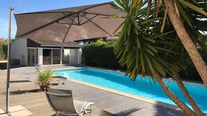 A modern house with a swimming pool, a covered patio, and a palm tree. - Beautiful Villa with Large Heated Pool and Sea Water, 5 km from the Beach (Portiragnes)