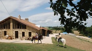 A stone building with a sloped roof, a horse, and a rider.
