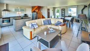 Een moderne woonkamer met een beige bank, een salontafel en een eethoek met een tafel en stoelen.