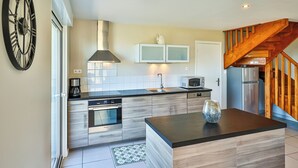 Een moderne keuken met roestvrijstalen apparatuur, houten kasten en een centraal kookeiland.