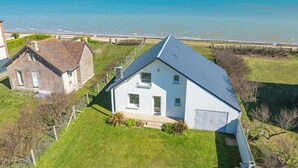 Een pand aan de kust met een wit huis, een stenen gebouw en uitzicht op zee.