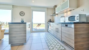 Een moderne keuken met een vast kookeiland, roestvrijstalen apparatuur en een groot raam met uitzicht op de omgeving.