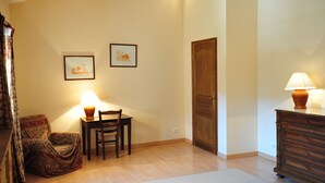 Ein Zimmer mit Holzboden, einem Esstisch mit Stühlen, einem Holzschrank und zwei gerahmten Bildern an der Wand.