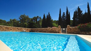 Ein klares, blaues Schwimmbecken mit Steinmauern und hohen Bäumen im Hintergrund.