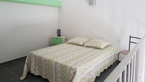 A small, clean room with a bed, a nightstand, and a lamp.