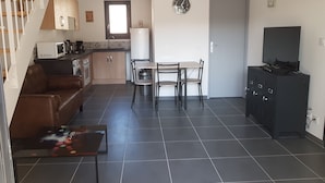 A compact living space with a kitchenette, a dining area, a sofa, a coffee table, and a TV.