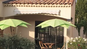 A patio with two green umbrellas, a wooden table, and chairs.