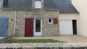A stone building with a sloped roof, a white door, and a garage door.