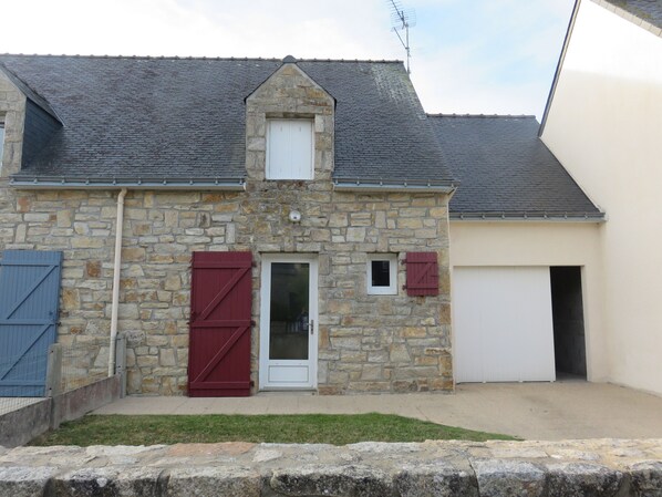 A stone building with a sloped roof, a white door, and a garage door.