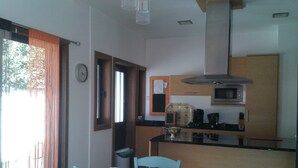 A compact kitchen with a microwave, coffee maker, and a small dining area with a table and chairs. - Near the beach, detached single-storey house, enclosed garden, nearby golf course (Vila Nova de Gaia)