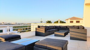 Una terraza en la azotea con un sofá modular, dos otomanas y una mesa de centro.