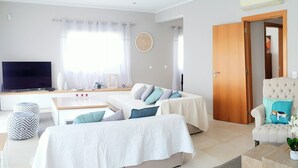 Una sala de estar moderna con un conjunto de sofá, una mesa de centro, un televisor y una puerta que conduce a otra habitación.