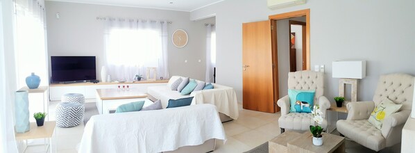 A modern living room with a sofa set, a coffee table, a television, and a door leading to another room. - Luxury Villa with sea view rooftop & swimming pool at 900m from the beach (Portimão)