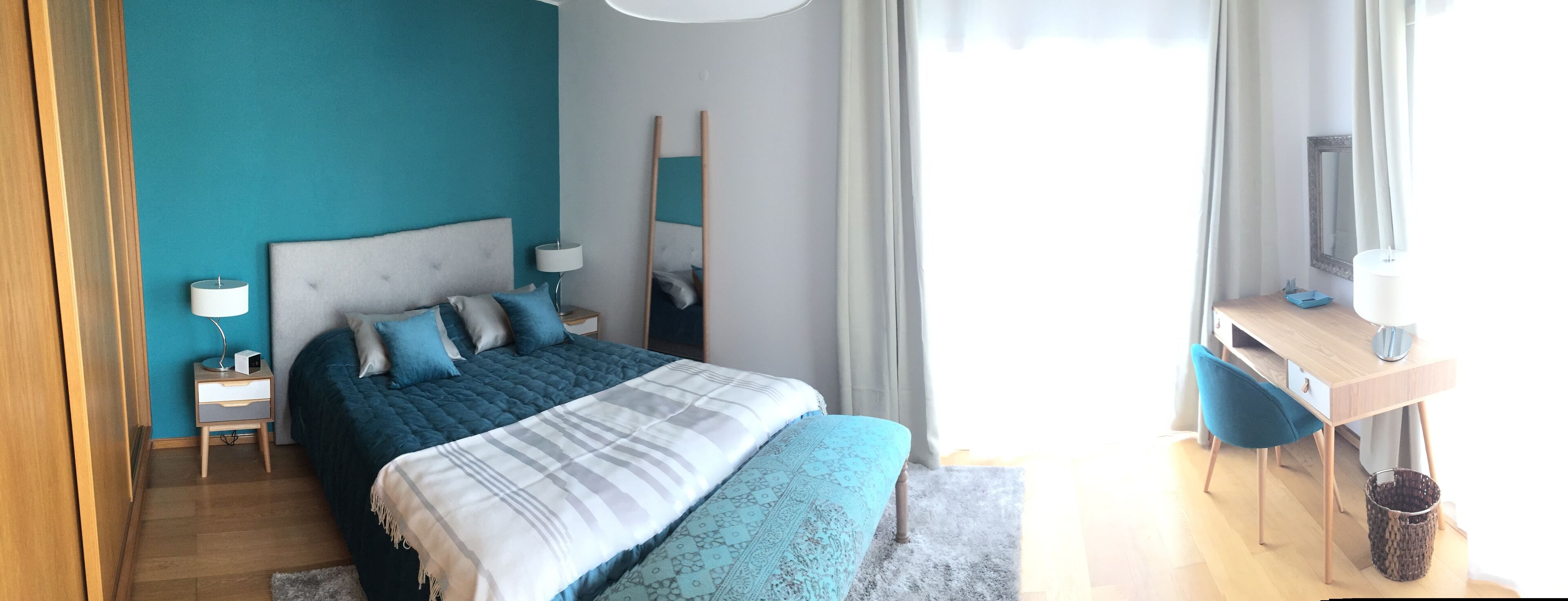 A modern bedroom with a large bed, bedside tables, a desk, and a chair.