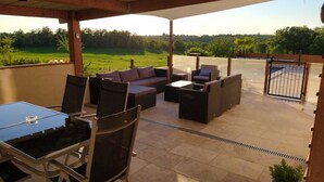 Un patio techado al aire libre con una mesa de comedor y sillas, un sofá y una mesita.