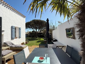 A patio with a table, chairs, and a small garden area. - Maisonsdouces KERGANE Le Vieil, La Madeleine, 10 meters from the beach, on the Dune (Noirmoutier-en-l'Ile)