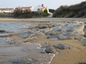 A beach with large rocks and a building in the background.