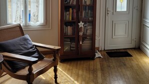 Een kamer met een houten stoel, een boekenkast en een deur met een decoratief glasraam.