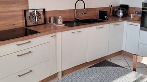 Een moderne keuken met een zwarte spoelbak, witte kasten en een blauwe accentmuur.