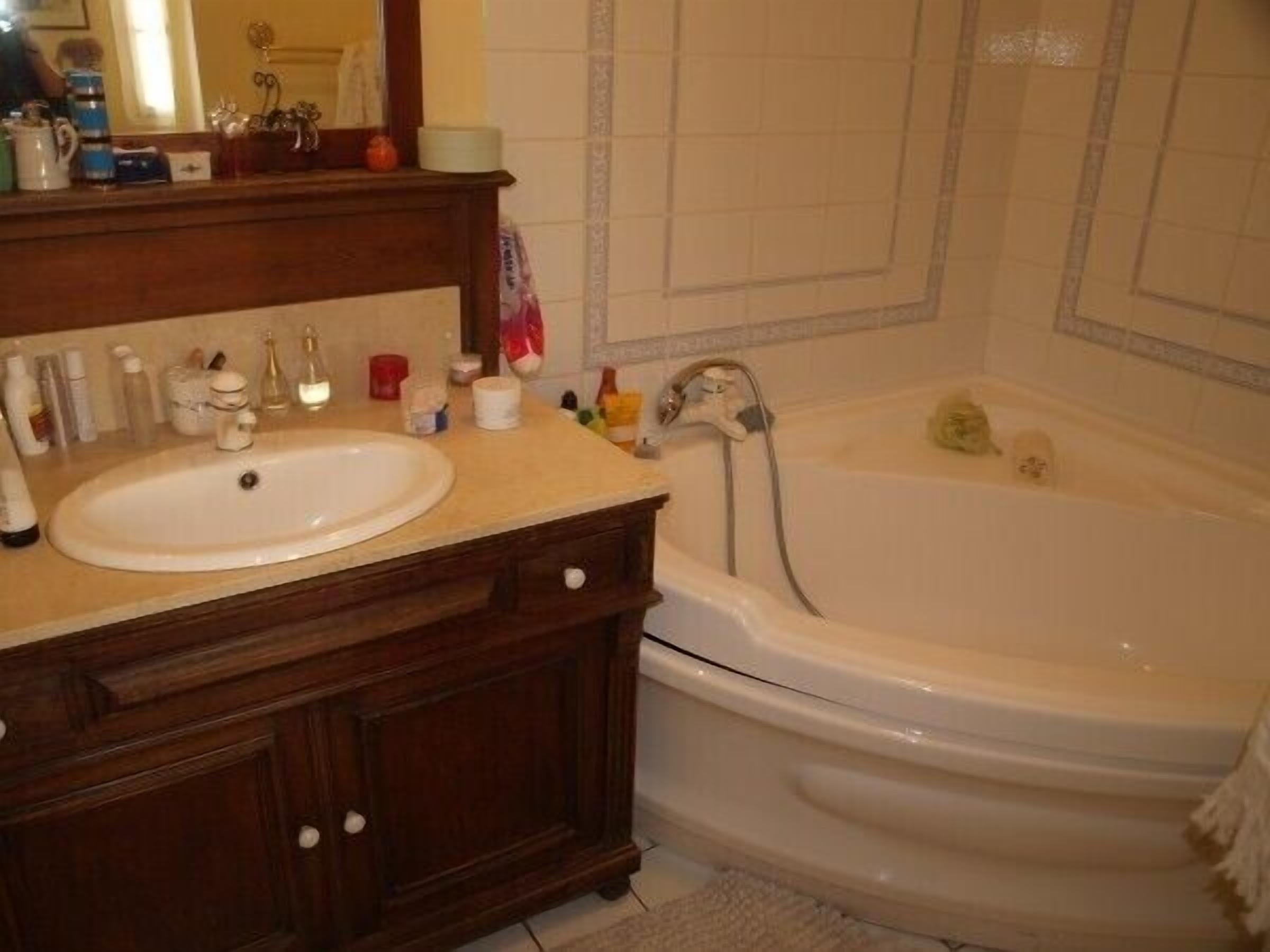 Un baño con lavamanos blanco, tocador de madera y bañera.