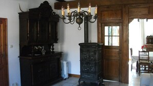 A rustic room with exposed wooden beams, a large dark wooden cabinet, a black stove, and a white sofa. - Charming cottage classified 3 stars in an old renovated mill. Comfort. (Schoenbourg)