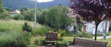 A bench and a chair in a garden area with a paved walkway.