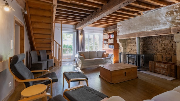 A cozy living room with wooden beams, a fireplace, and comfortable seating.