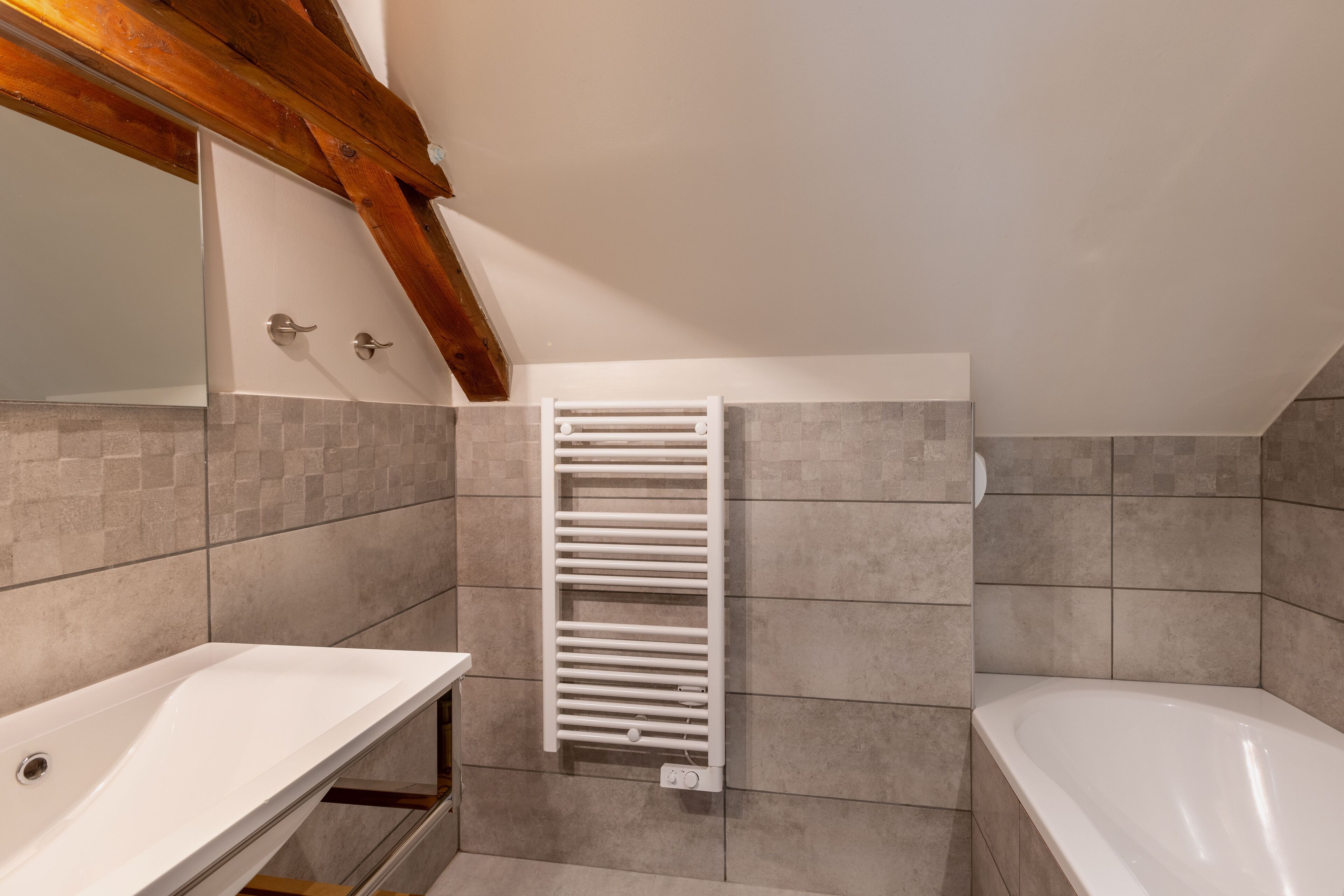 A bathroom with a white bathtub, a white sink, and a towel rack.
