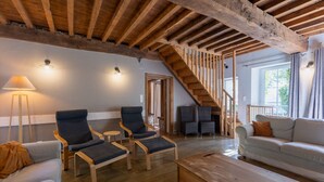 A spacious living area with wooden beams, a staircase, and a sofa.
