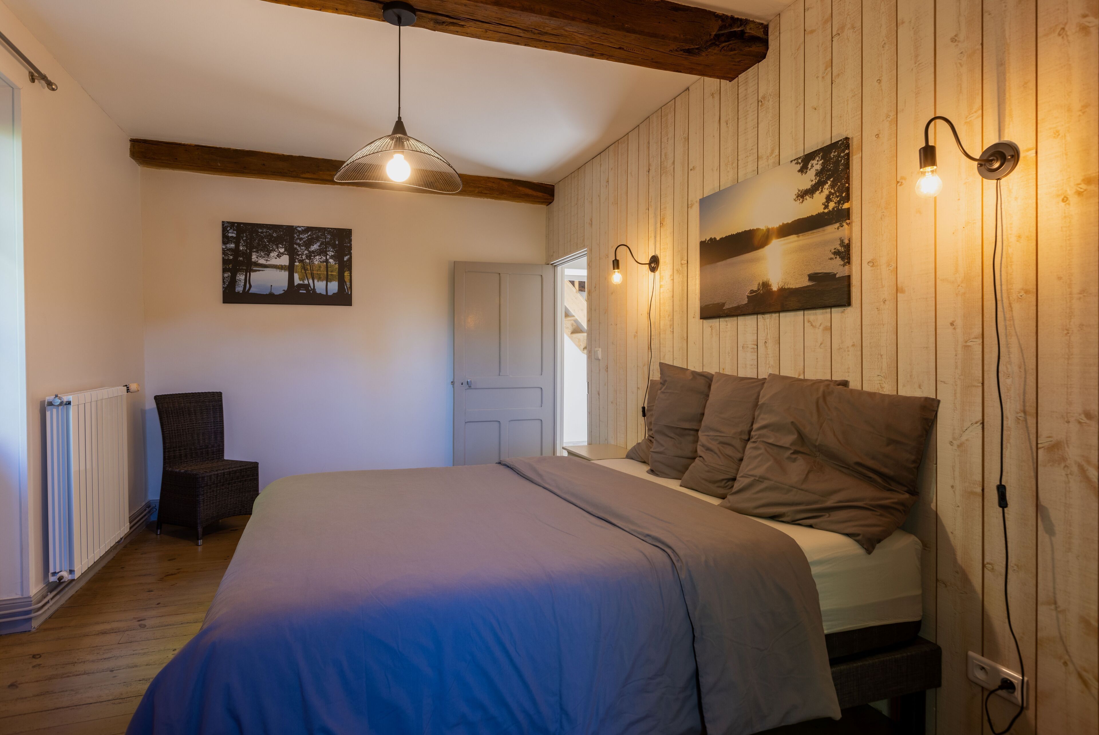 Une chambre à coucher comprenant un lit, une chaise, un radiateur et des luminaires fixés au mur.