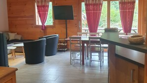 Un interior de madera con una zona de comedor, un sofá y un televisor.
