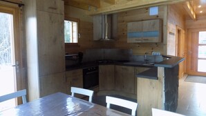 Una cocina moderna con armarios de madera, un lavamanos de acero inoxidable y un comedor con mesa y sillas.